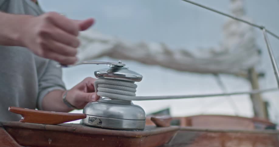 Man turning a crank attached to a rope on a boat