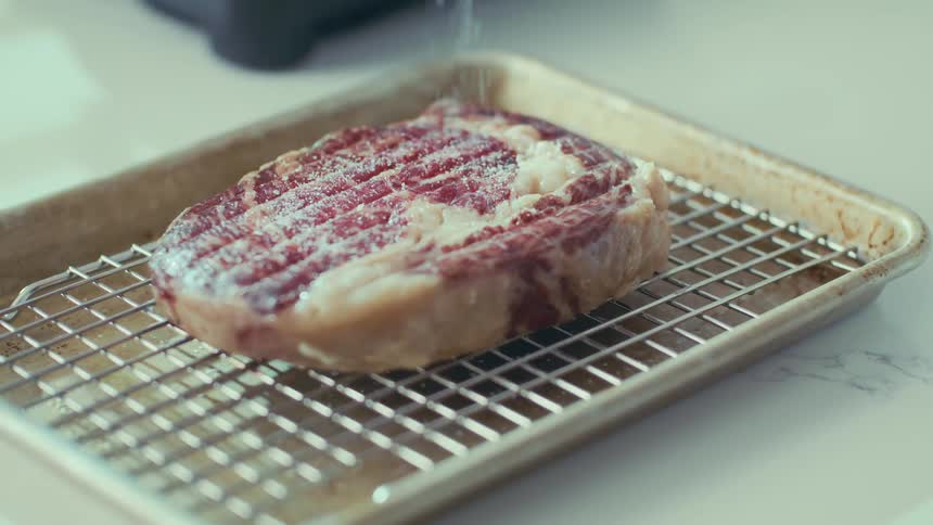 Salt is being sprinkled on the steak