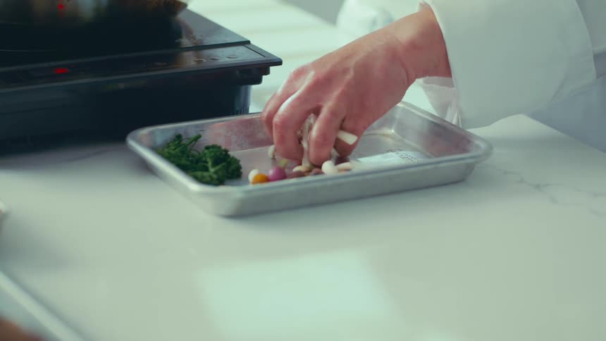 Hand picking up raw mushrooms on top of a metal container