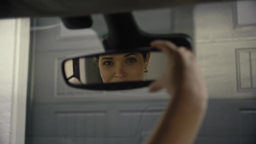A woman turns the mirror and smiles into it