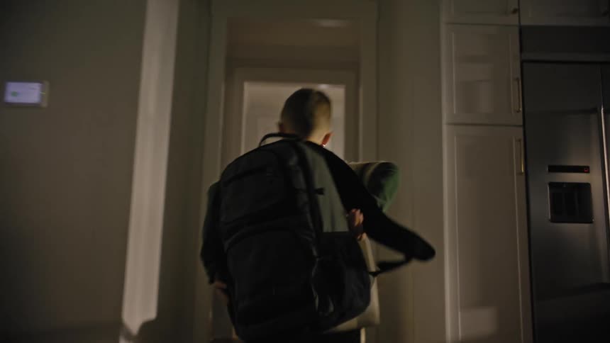 Boy running down the stairs of his house and out the door with his dog