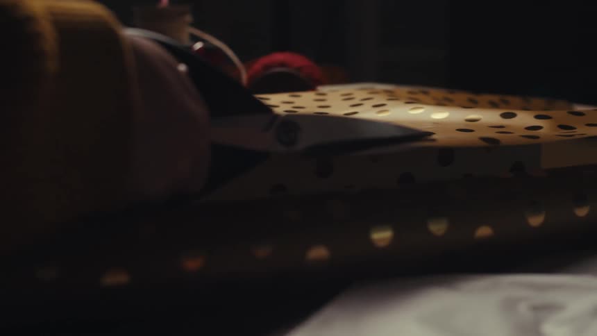 Closeup of hands cutting bright gold paper to wrap a present