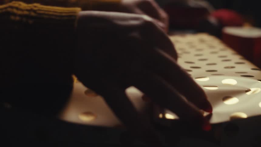 Closeup of hands wrapping a present in bright gold paper