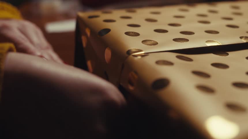 A person is wrapping a gift with wrapping paper