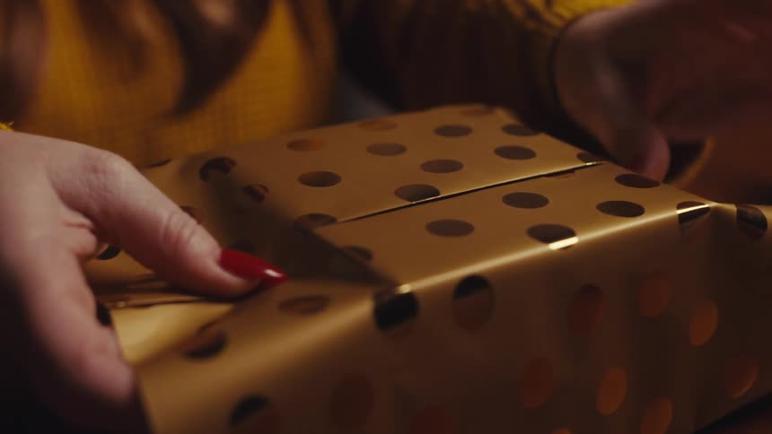 Wrapping a small box with gold and gold polka dots wrapping paper