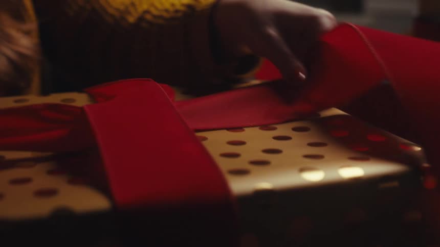 Wrapping a wide red ribbon around a box with polka dots gift wrapping