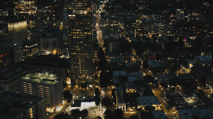 The city is brightly lit at night and has heavy clouds above