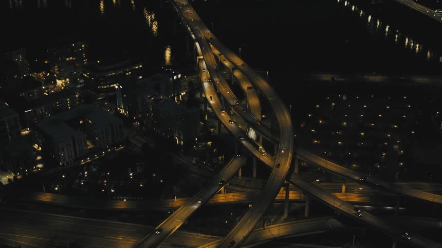 A network of illuminated highways crisscrosses a city at night
