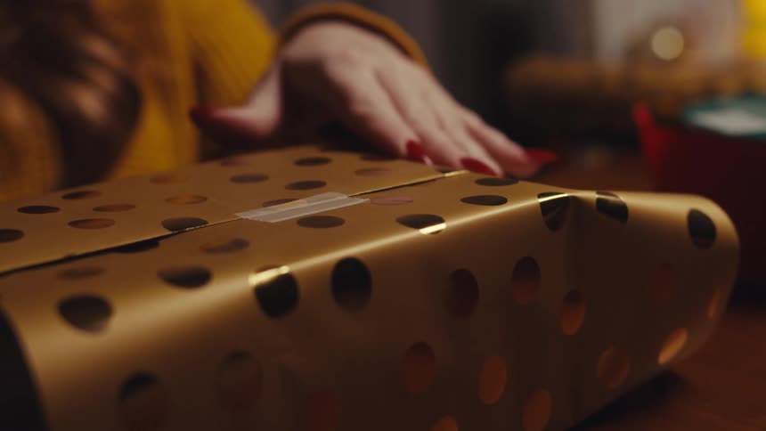 A woman is using tape to wrap a gift