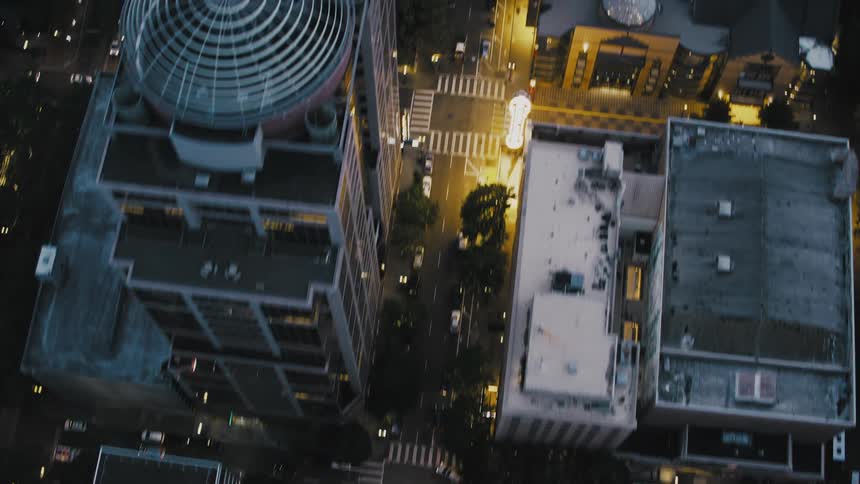 Cars drive past the buildings in the city at night
