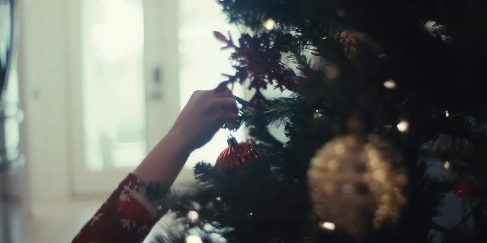 A child hangs an ornament on a christmas tree