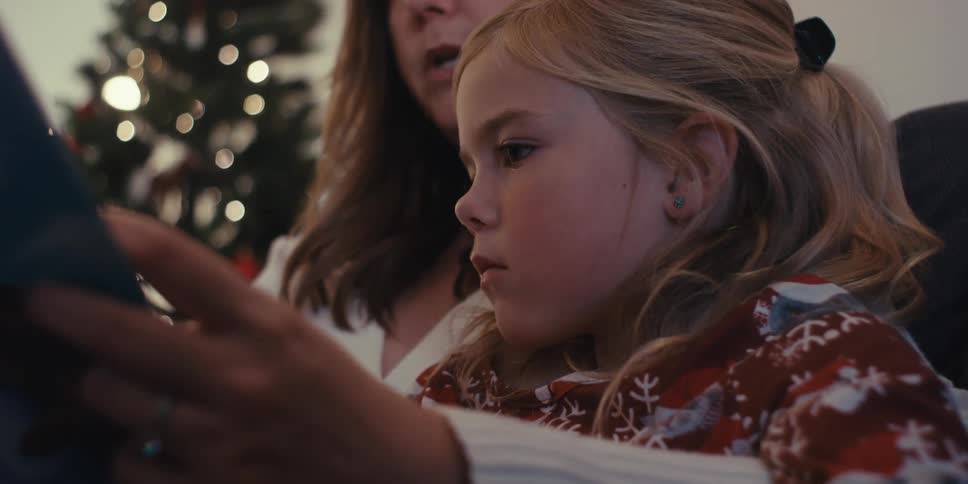 Mother reads her daughter a story during the christmas season