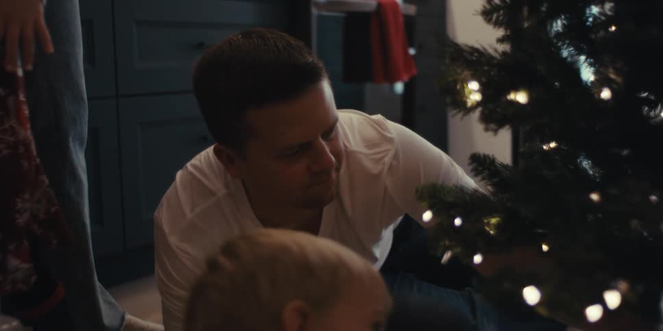 Children watch as their father moves the christmas tree