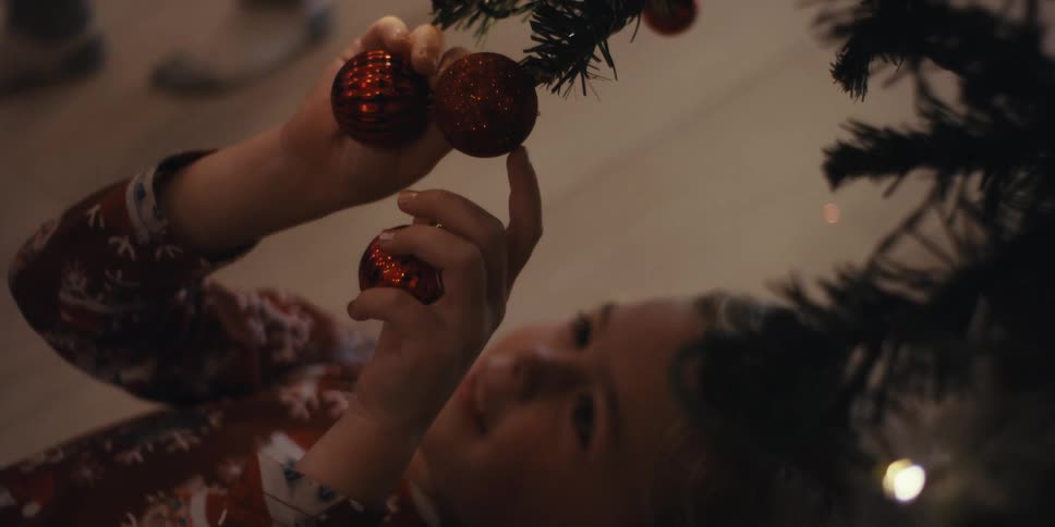 A child plays with christmas ornaments under the tree