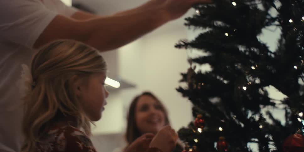 Family setting up a christmas tree indoors