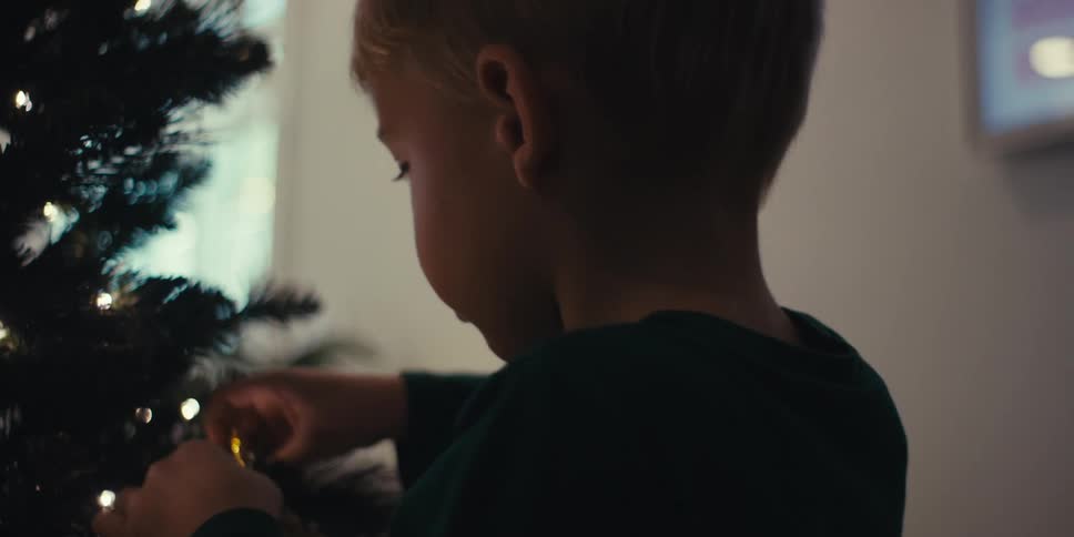 Little boy putting a decoration on a christmas tree