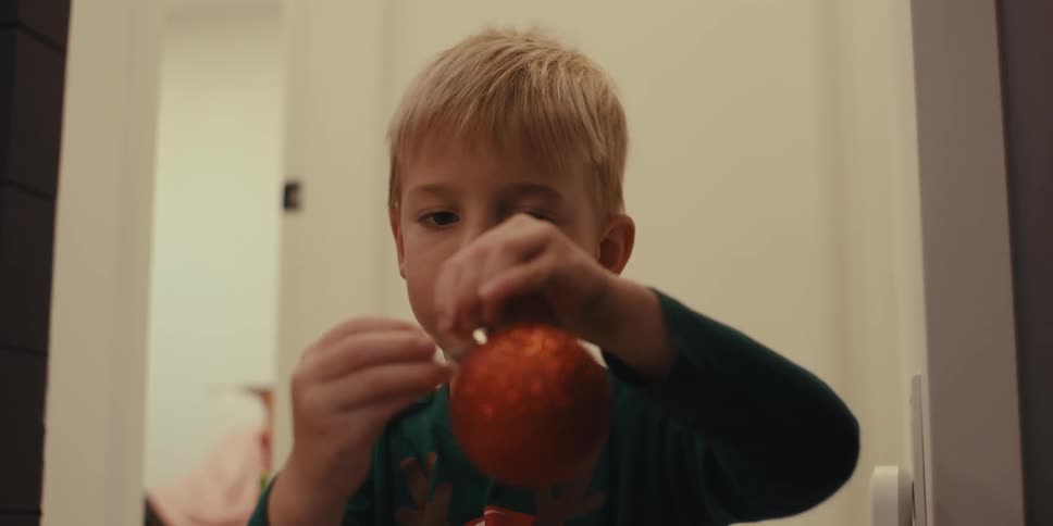 Little boy putting a hook on a christmas ball ornament