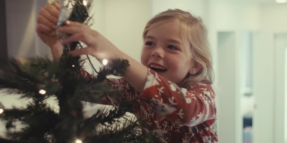 A girl laughs as she puts the star on the christmas tree