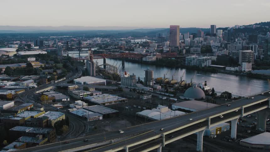 An aerial view of a metropolitan city with a huge highway with cars passing over a water channel