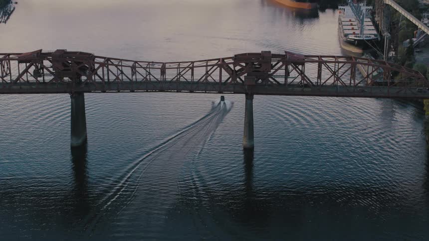 A speed boat travels under the bridge