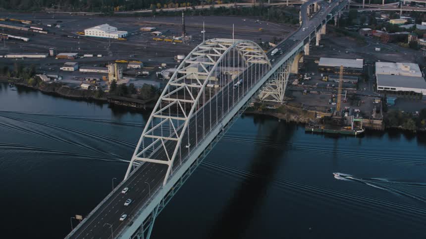 Traffic flows with cars on the bridge and boats underneath
