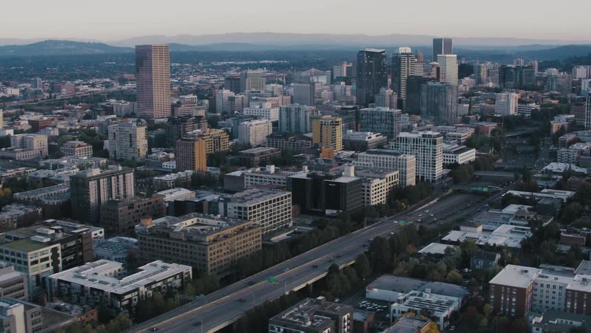 An aerial view of portland oregon showcasing a dense urban landscape with highrise buildings and a network of highways weaving through the city