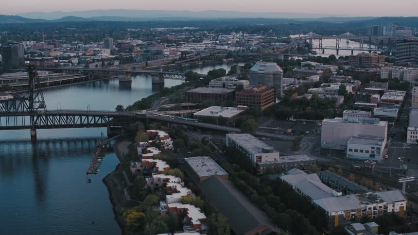An aerial view of a city with a large water canal on the left side and a large bridge passing over it