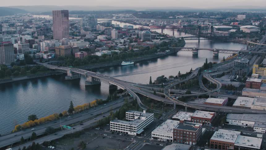 A panoramic view of a city skyline at dusk with bridges spanning a river