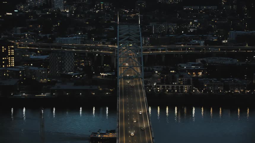 A bridge over a river by a city at night