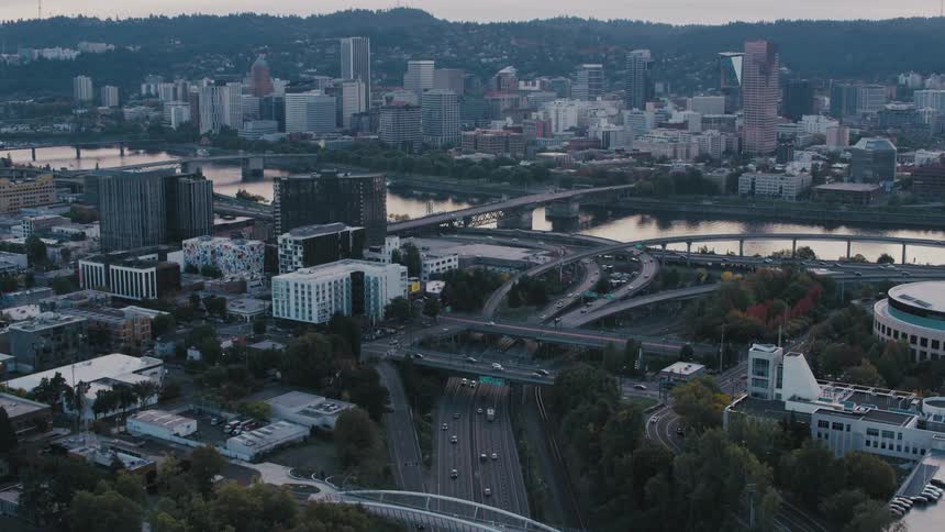 An aerial view showed a large metropolitan city with a huge highway full of vehicles and there is a water channel in the middle of the city