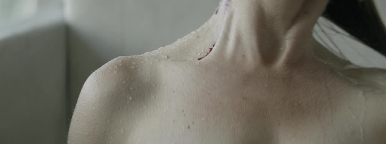 Blood drips down a woman's neck in the shower