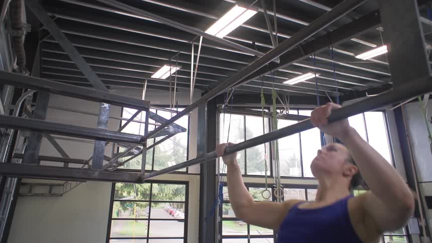 A woman does pull ups in a gym