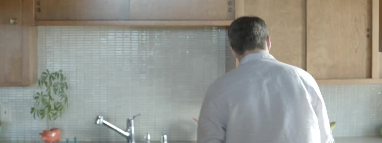 A man removes a plate from the table and puts it in the dishwasher