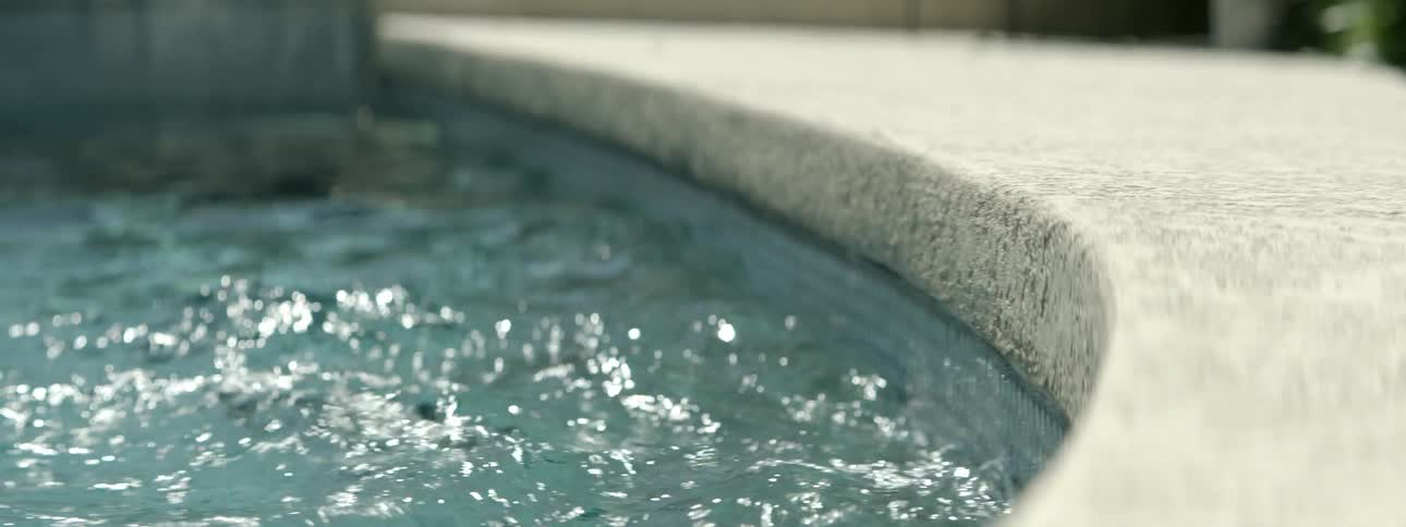 Pool water splashes against the side of the pool during the day