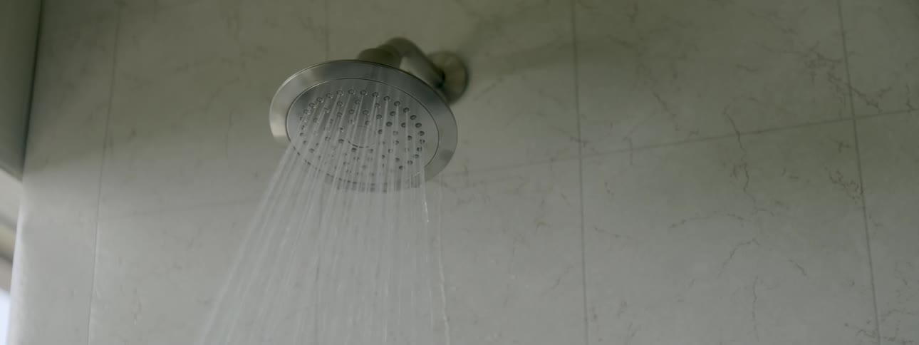 A shower head turns on and sprays water