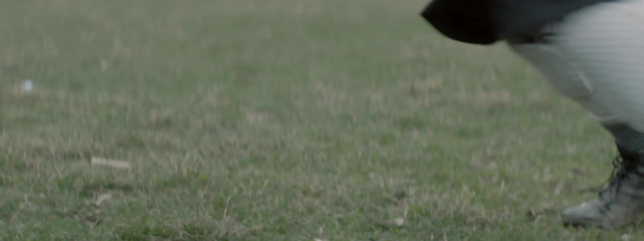 A person gets leverage in the grass wearing cleats