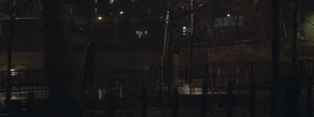 A man is walking his dog on the street at night