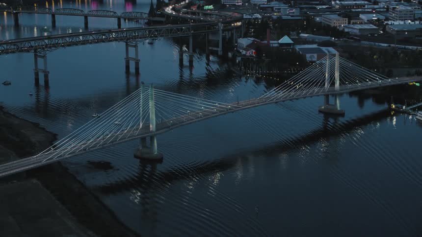 The tilikum crossing bridge with its distinctive cablestayed design spans the willamette river in portland oregon as seen from an aerial perspective at dusk