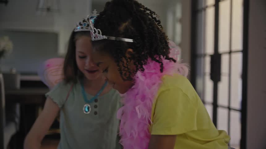 Two young girls play princess inside a house