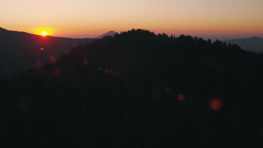 Silhouettes of mountains as the sun sets on the horizon