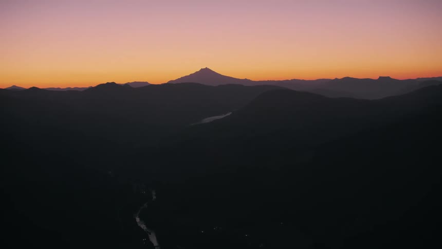 Aerial view of a narrow highway amidst the mountains on a purple sky dawn