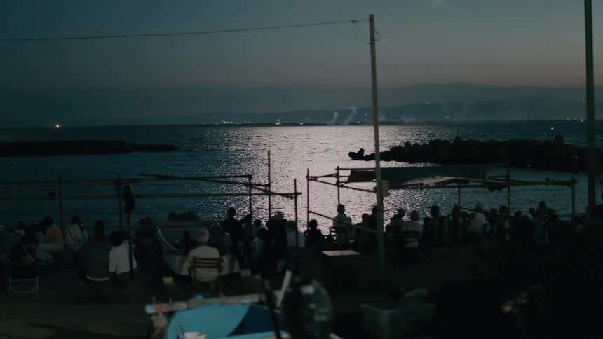 The fireworks reflect light on the water as people watch