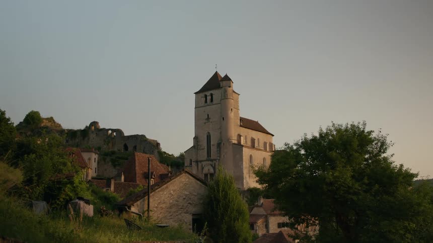 Fortification and cathedral tower over other buildings in a hillside town on a summer day