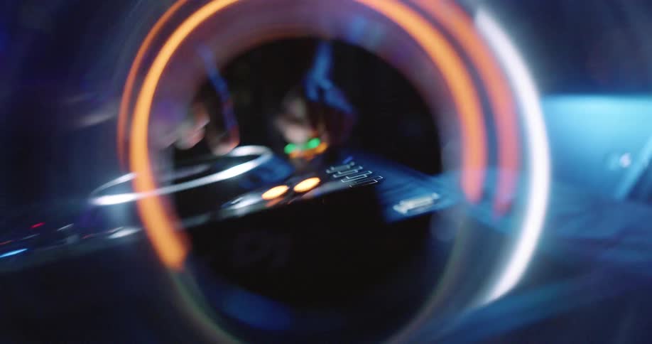 Artistic closeup of dj equipment seen through a ring light with a hand adjusting the controls