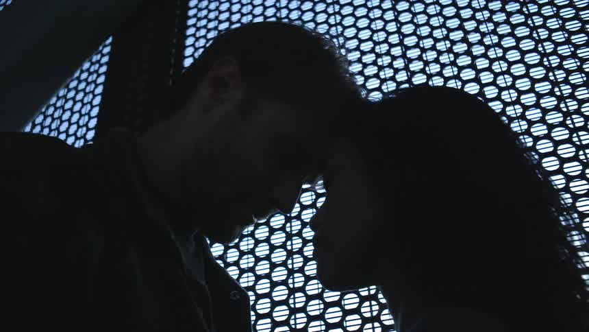 A man and woman are touching heads in the dark