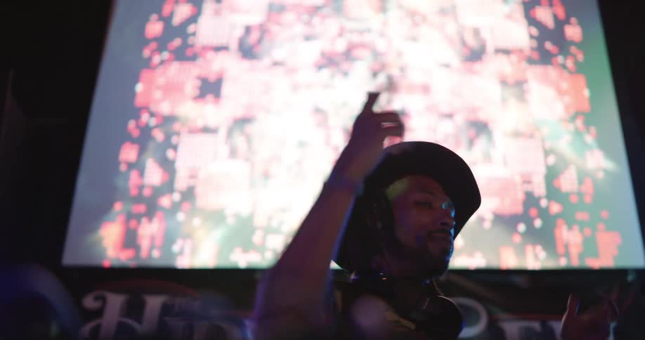 A man is djing in front of a screen