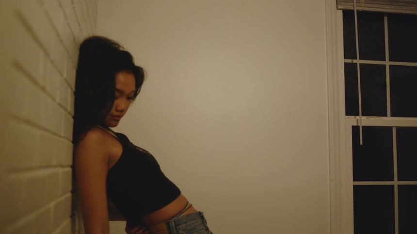 A woman leans and stretches against a brick wall