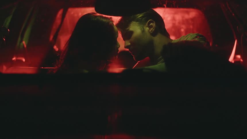 Man and woman in a car looking romantically and getting closer for a kiss