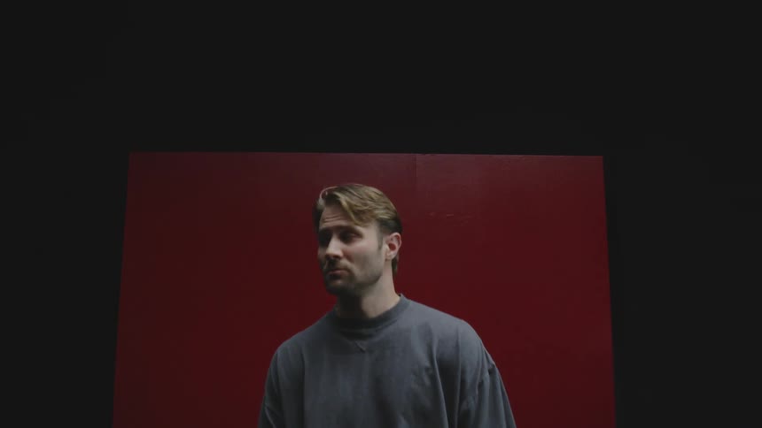 A man is standing in front of a red wall