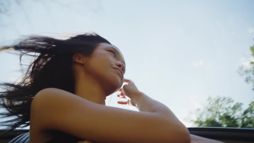 Woman with part of her body hanging out of a moving car